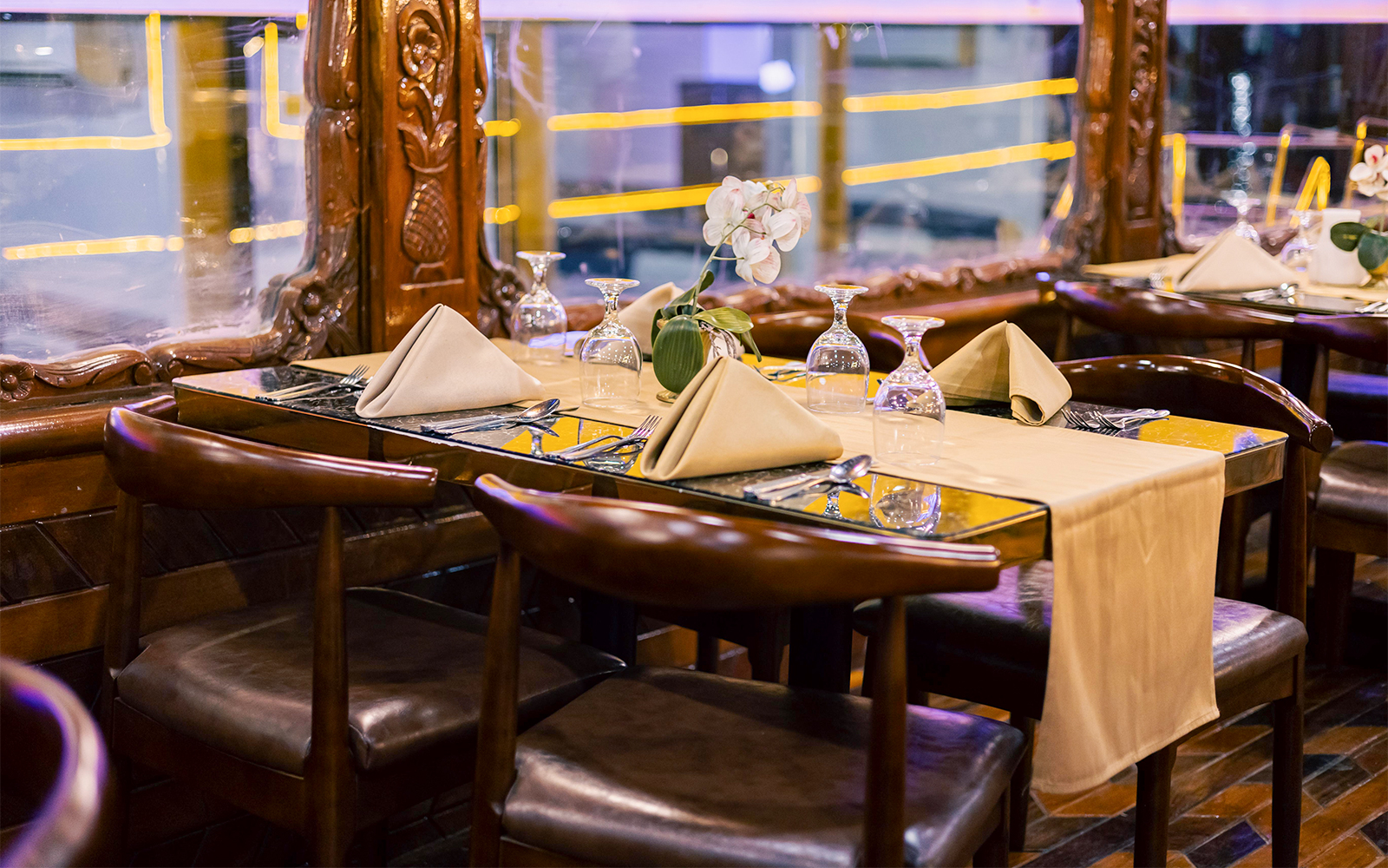 Elegant dining setup on Alexandra VIP Dhow Cruise with folded napkins and glassware.
