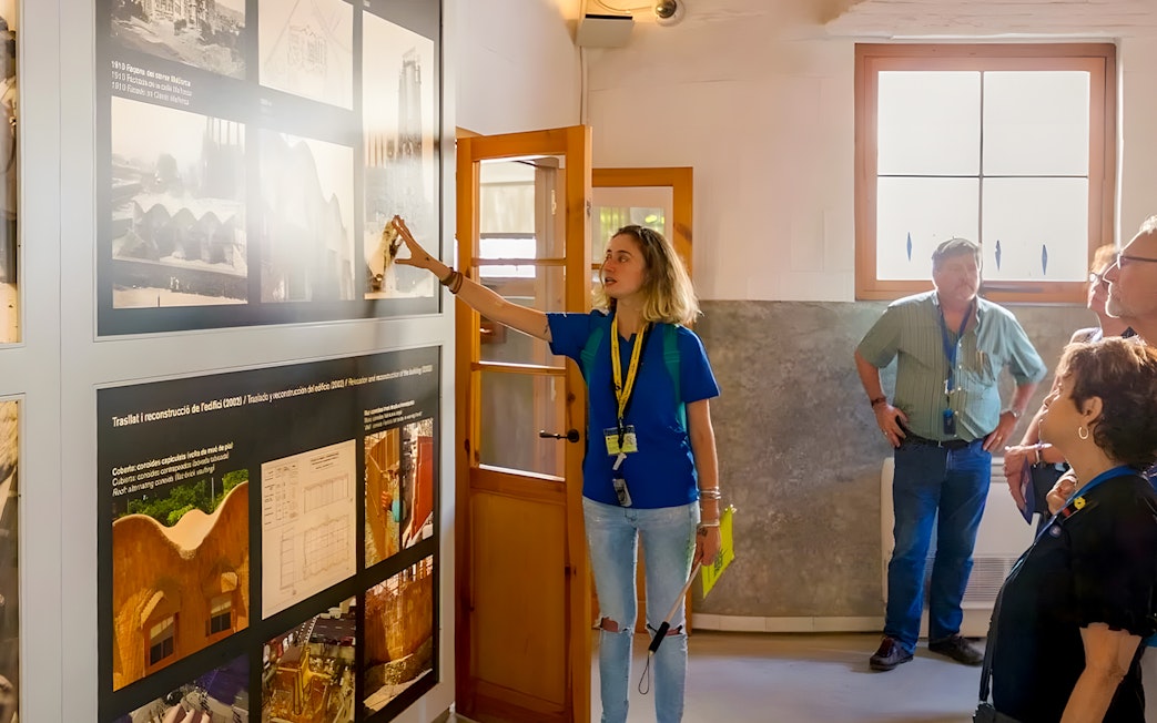 Guide explaining exhibits to tourists inside Sagrada Familia museum.