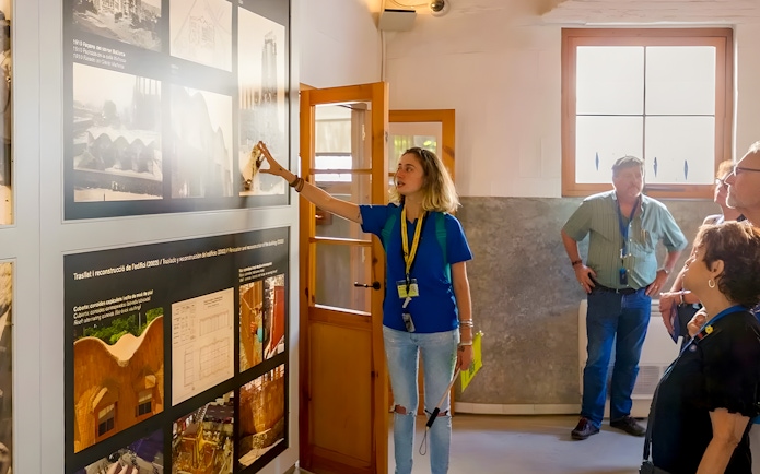 Guide explaining exhibits to tourists inside Sagrada Familia museum.