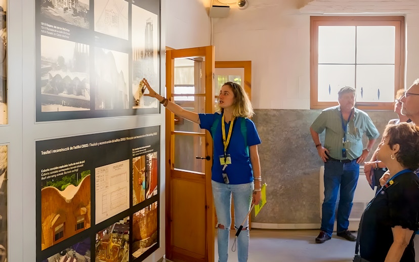 Guide explaining exhibits to tourists inside Sagrada Familia museum.