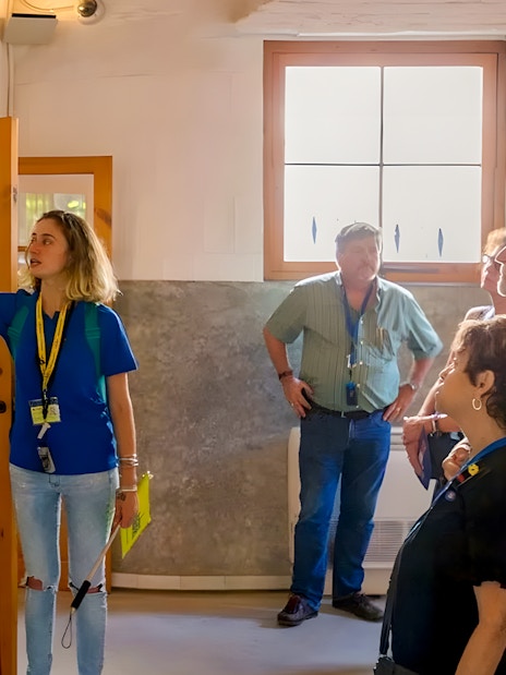 Guide explaining exhibits to tourists inside Sagrada Familia museum.
