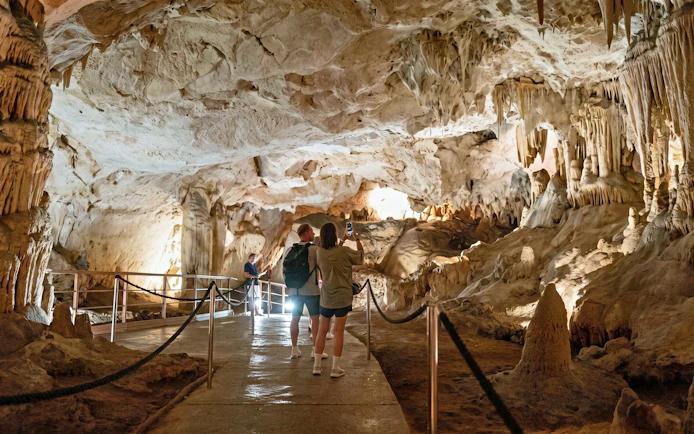 Visitors exploring the illuminated stalactites and stalagmites in the Caves of Nerja, Spain.