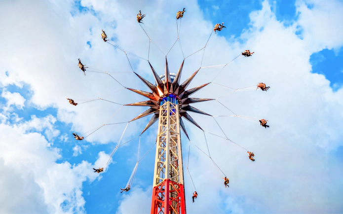 Thrill-seekers on a spinning ride at Six Flags, Mexico against a blue sky.