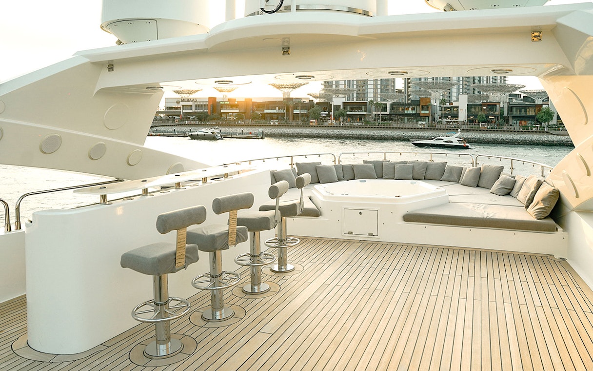 Sunseeker superyacht deck with bar stools, lounge seating, and waterfront view.