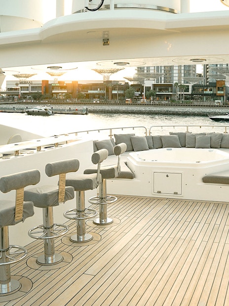 Sunseeker superyacht deck with bar stools, lounge seating, and waterfront view.
