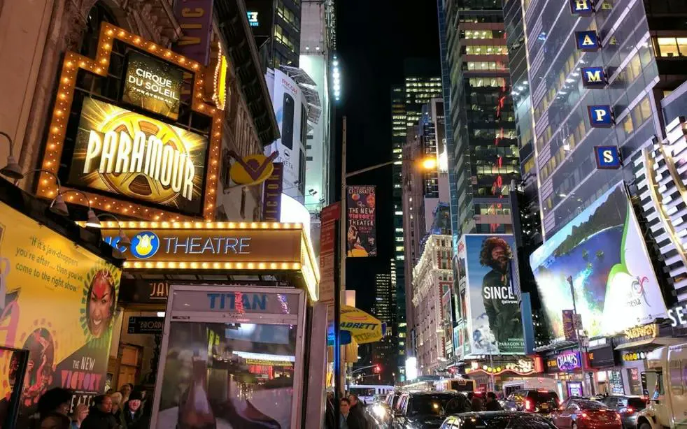 Broadway at night with theater signs and bustling street, New York City exploration game.