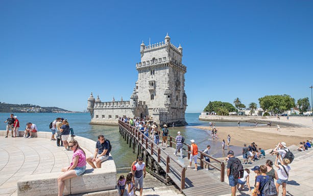 Visitors walking on a bridge to Belém Tower in Lisbon, Portugal.