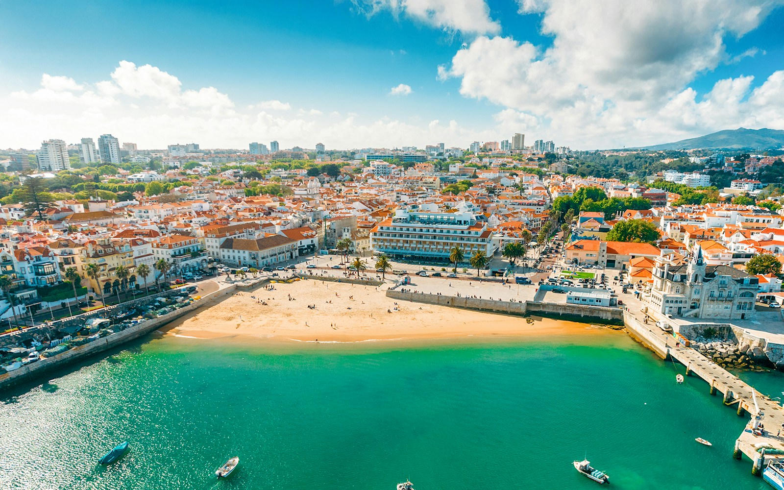 Aerial view of Cascais bay with sandy beach and town buildings, Portugal.