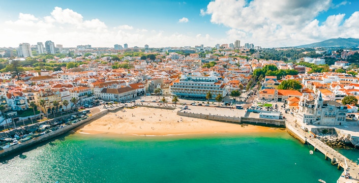 Aerial view of Cascais bay with sandy beach and town buildings, Portugal.
