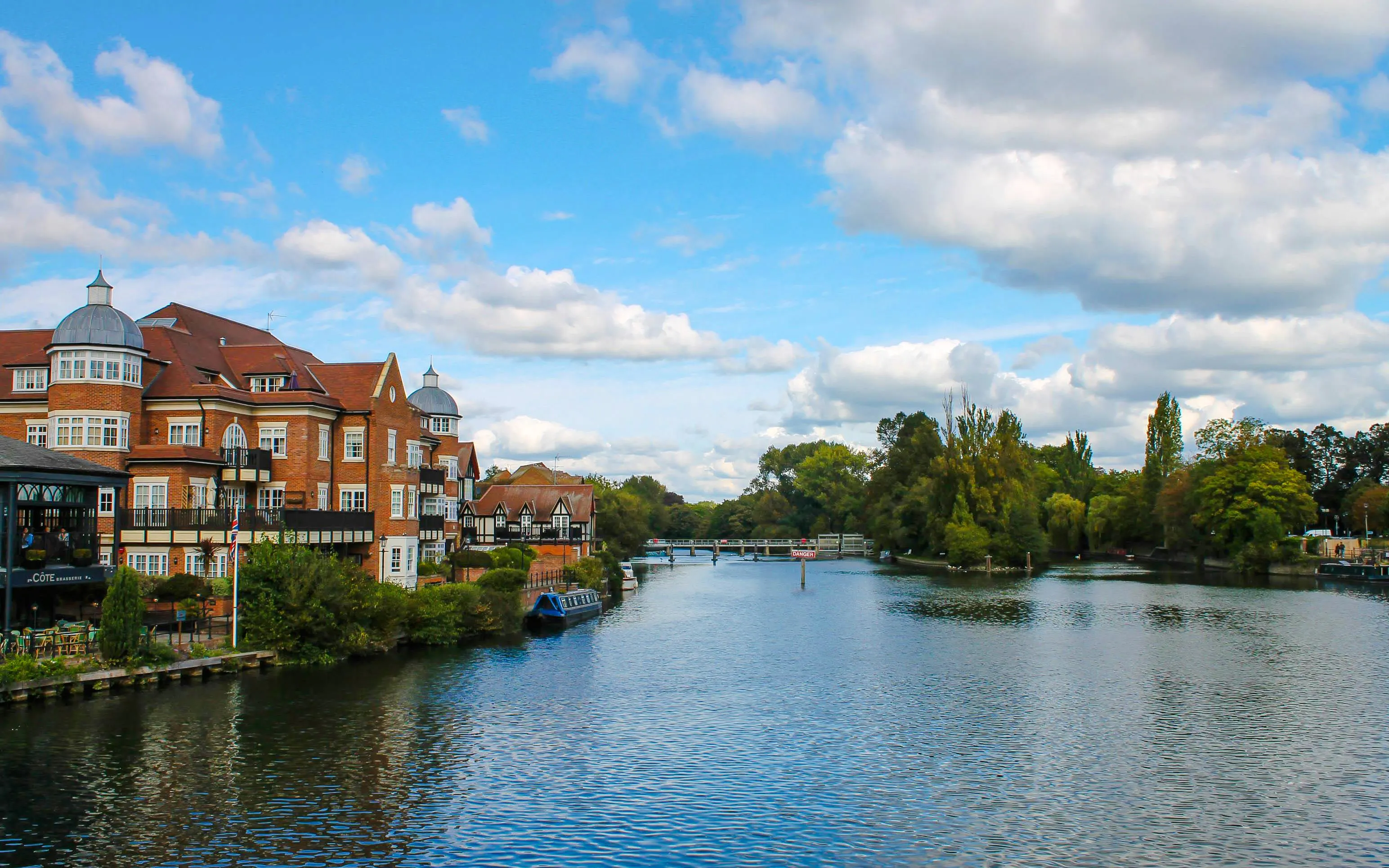 Riverside view of Eton Bridge with nearby buildings and lush greenery.