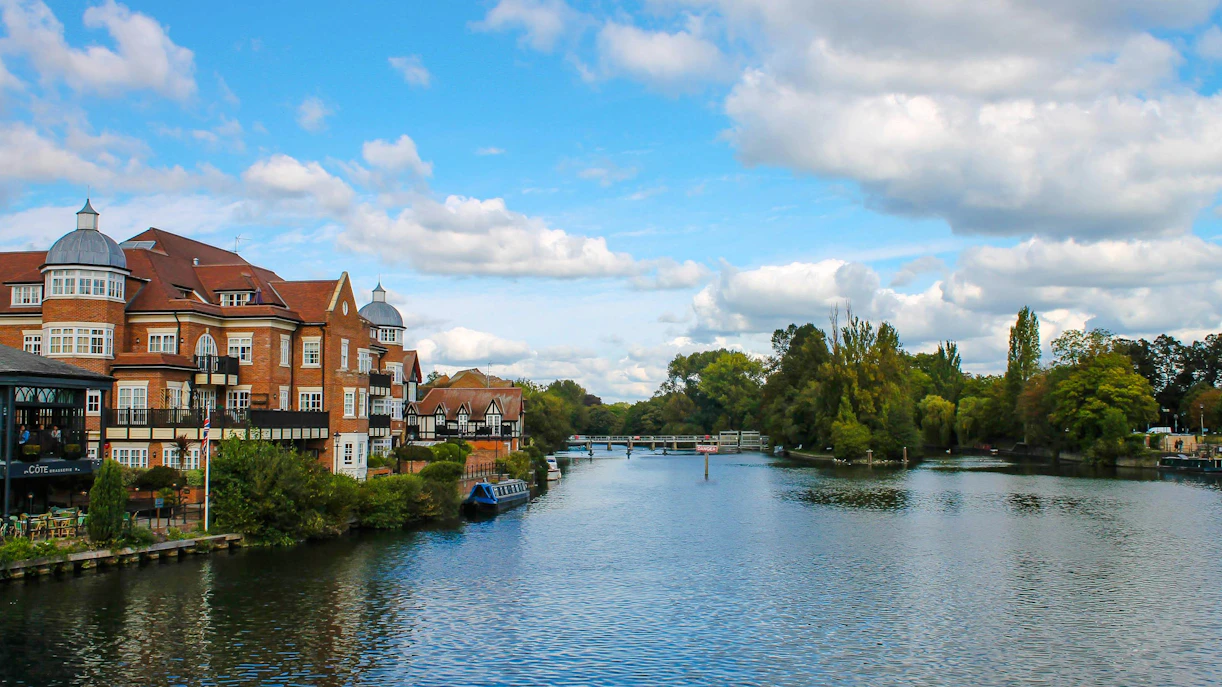 Riverside view of Eton Bridge with nearby buildings and lush greenery.