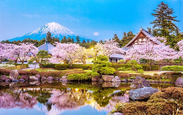 Mt. Fuji with cherry blossoms and traditional Japanese architecture in the foreground.