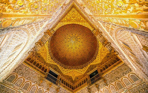Ornate ceiling of the Alcazar of Seville, showcasing intricate patterns and golden details.