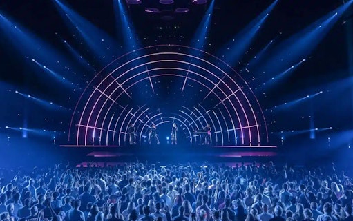 Crowd watching ABBA Voyage concert with illuminated stage and performers.