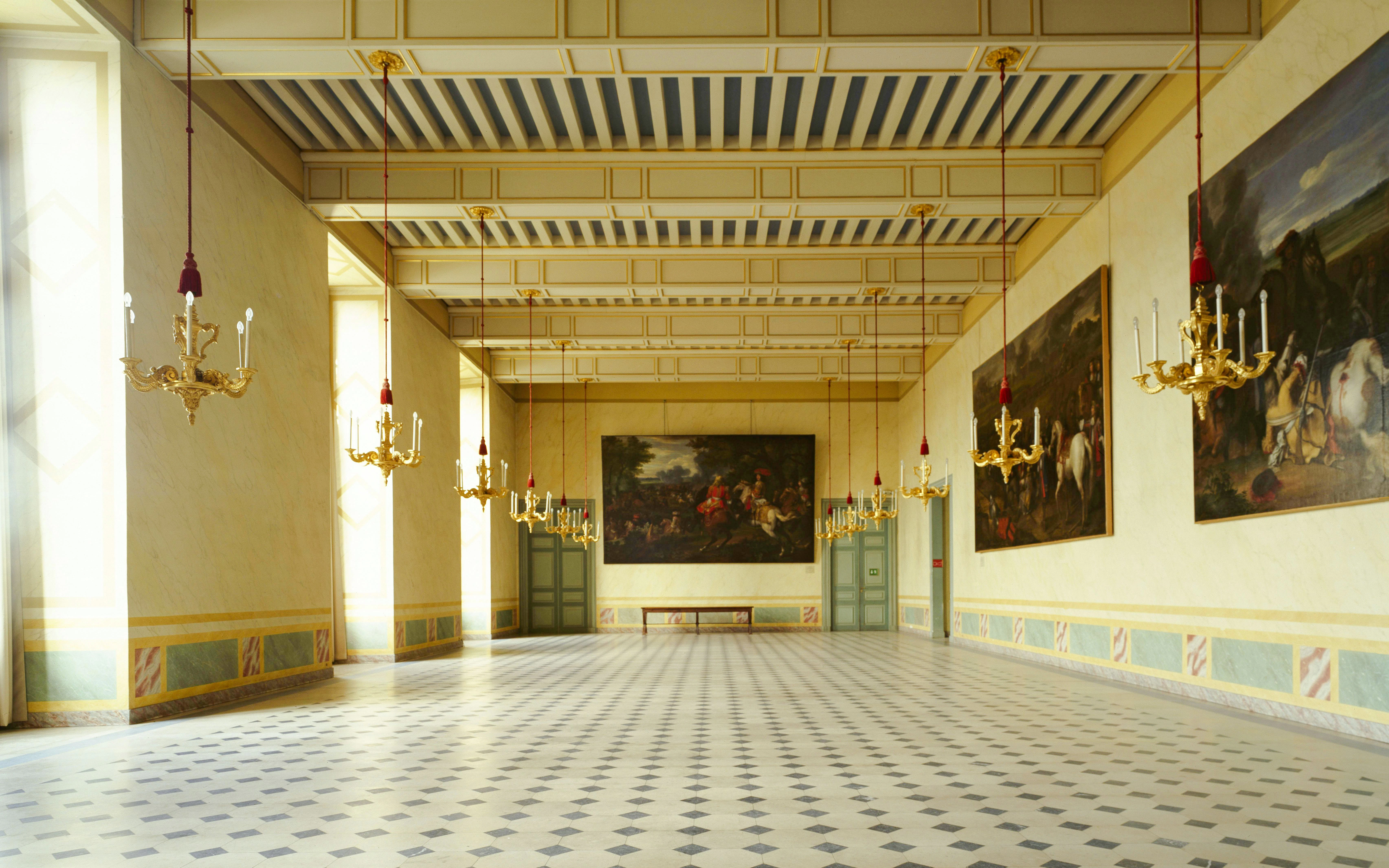 Interior of Château de Vincennes with chandeliers and historic paintings.