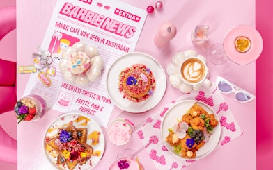 Barbie-themed cafe table with colorful desserts and drinks in Amsterdam.