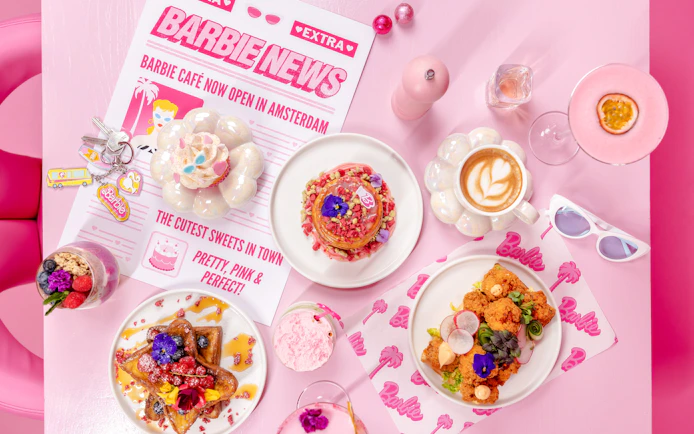 Barbie-themed cafe table with colorful desserts and drinks in Amsterdam.
