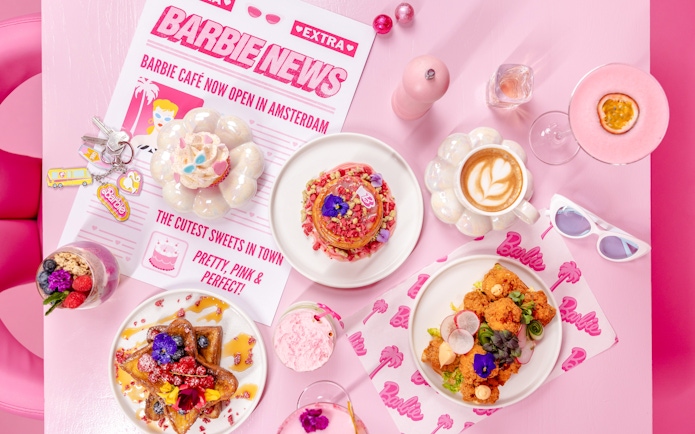Barbie-themed cafe table with colorful desserts and drinks in Amsterdam.