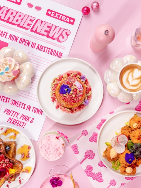Barbie-themed cafe table with colorful desserts and drinks in Amsterdam.