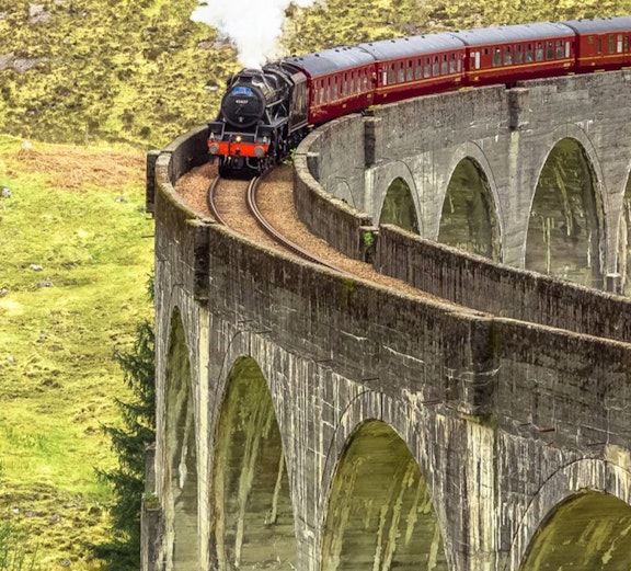 Steam train crossing the Glenfinnan Viaduct in Isle of Skye, Scotland.
