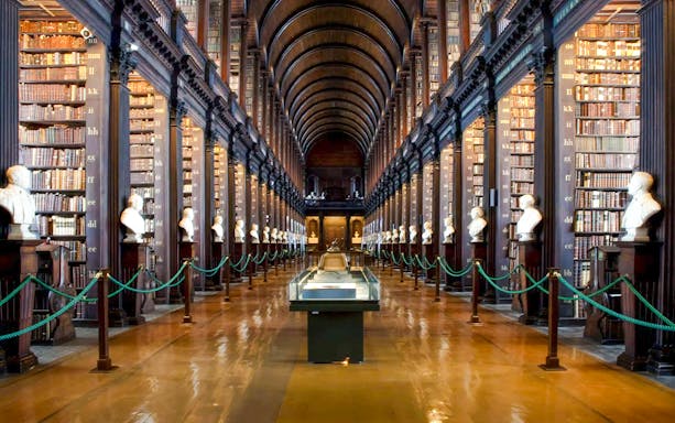 Interior of the Long Room, Trinity College Library, with rows of antique books and wooden shelves.