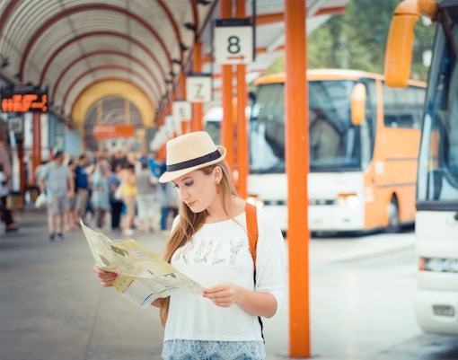 Jeune fille en voyage qui attend un bus à la gare routière. Voyage en Europe.