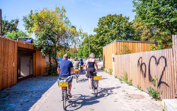 Cyclists on a guided tour ride through a graffiti-lined street in Berlin.