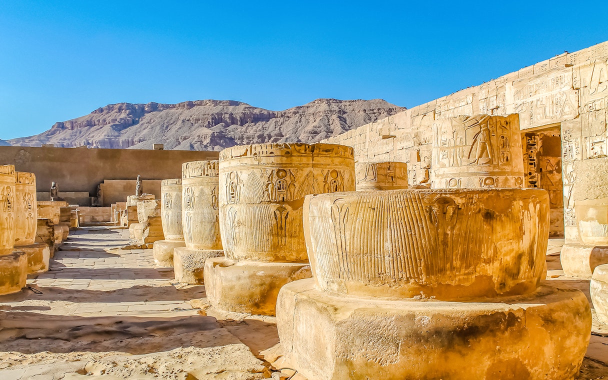 Ancient columns and hieroglyphs at Luxor Temple, Egypt, with desert mountains in the background.