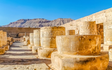 Ancient columns and hieroglyphs at Luxor Temple, Egypt, with desert mountains in the background.