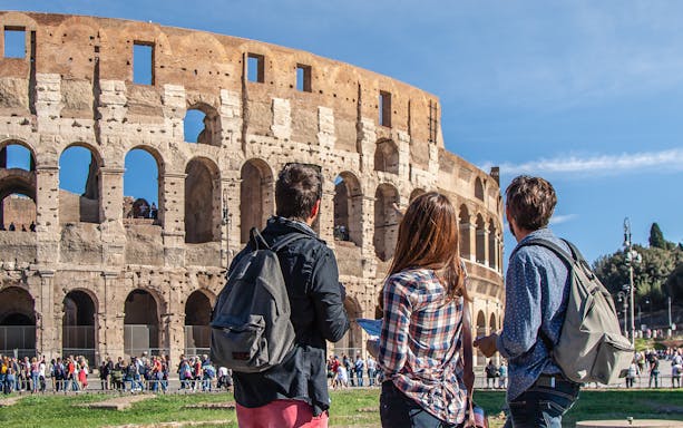 Tourists with backpacks admire the Colosseum during an E-Bike City Center Tour of Rome.