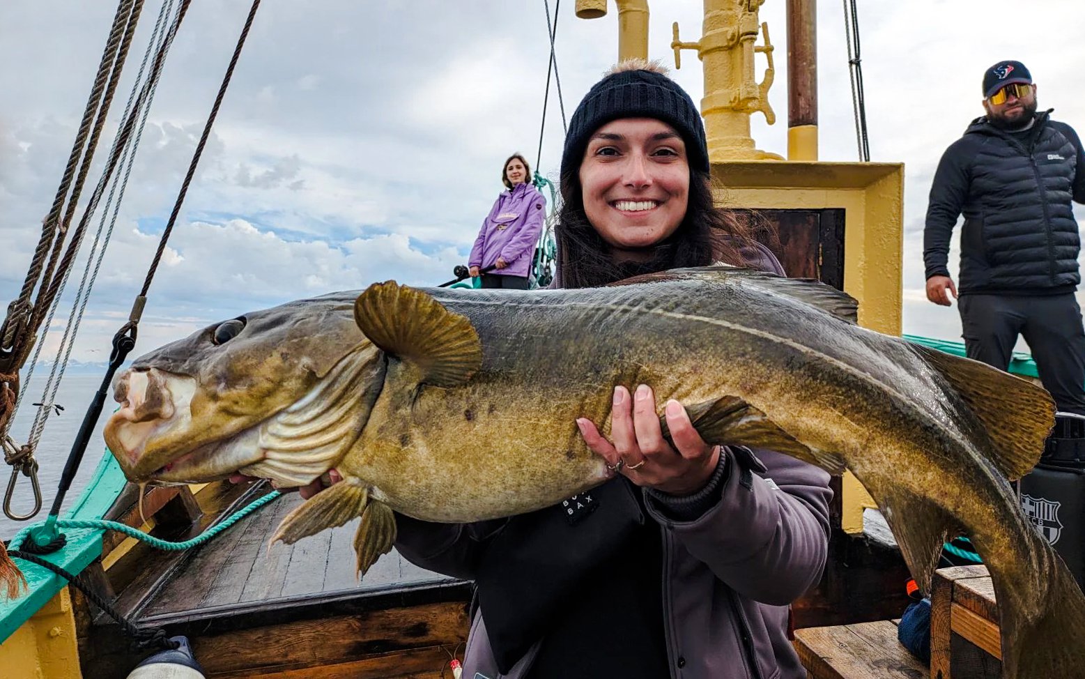 Woman holding Atlantic cod on fishing boat cruise, Lofoten.