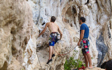Rock climbers scaling limestone cliffs at Railay Beach, Krabi during a climbing course.