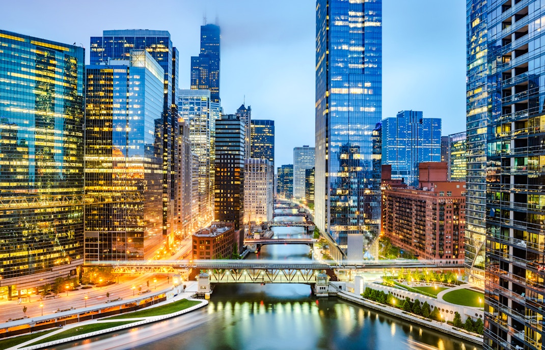 Chicago downtown skyline at dusk viewed from Wolf Point with illuminated skyscrapers and river.