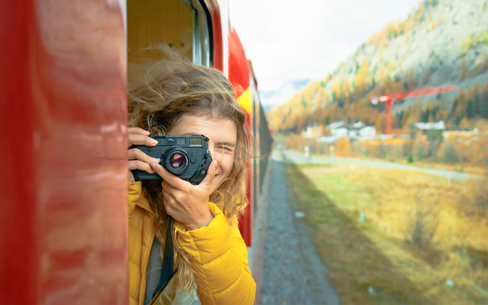 A photographer leaning out of bernina red train train to click photos of the lake.