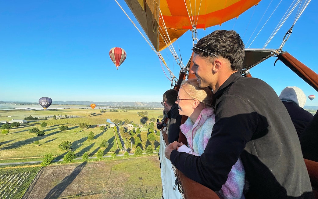 Hot air balloon ride over Yarra Valley at sunrise with passengers enjoying the view.