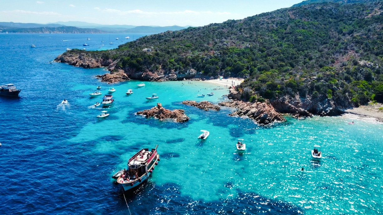 Motorboats exploring the turquoise waters of La Maddalena Archipelago, Italy.