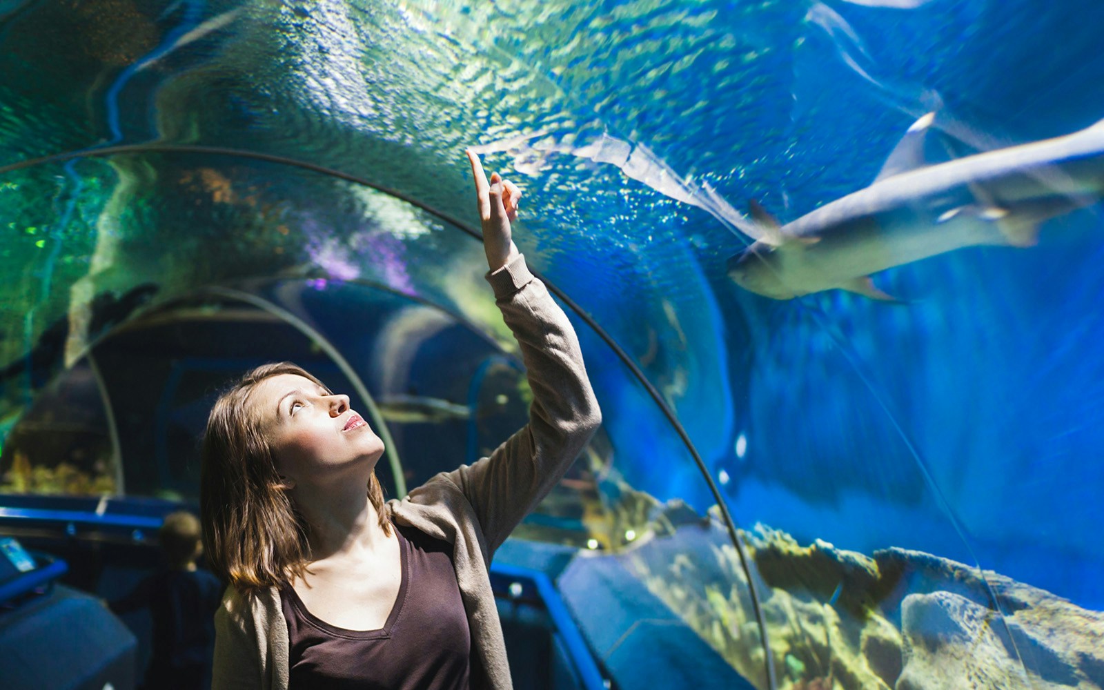 Girl walking through underwater tunnel at Cattolica Aquarium, Italy.