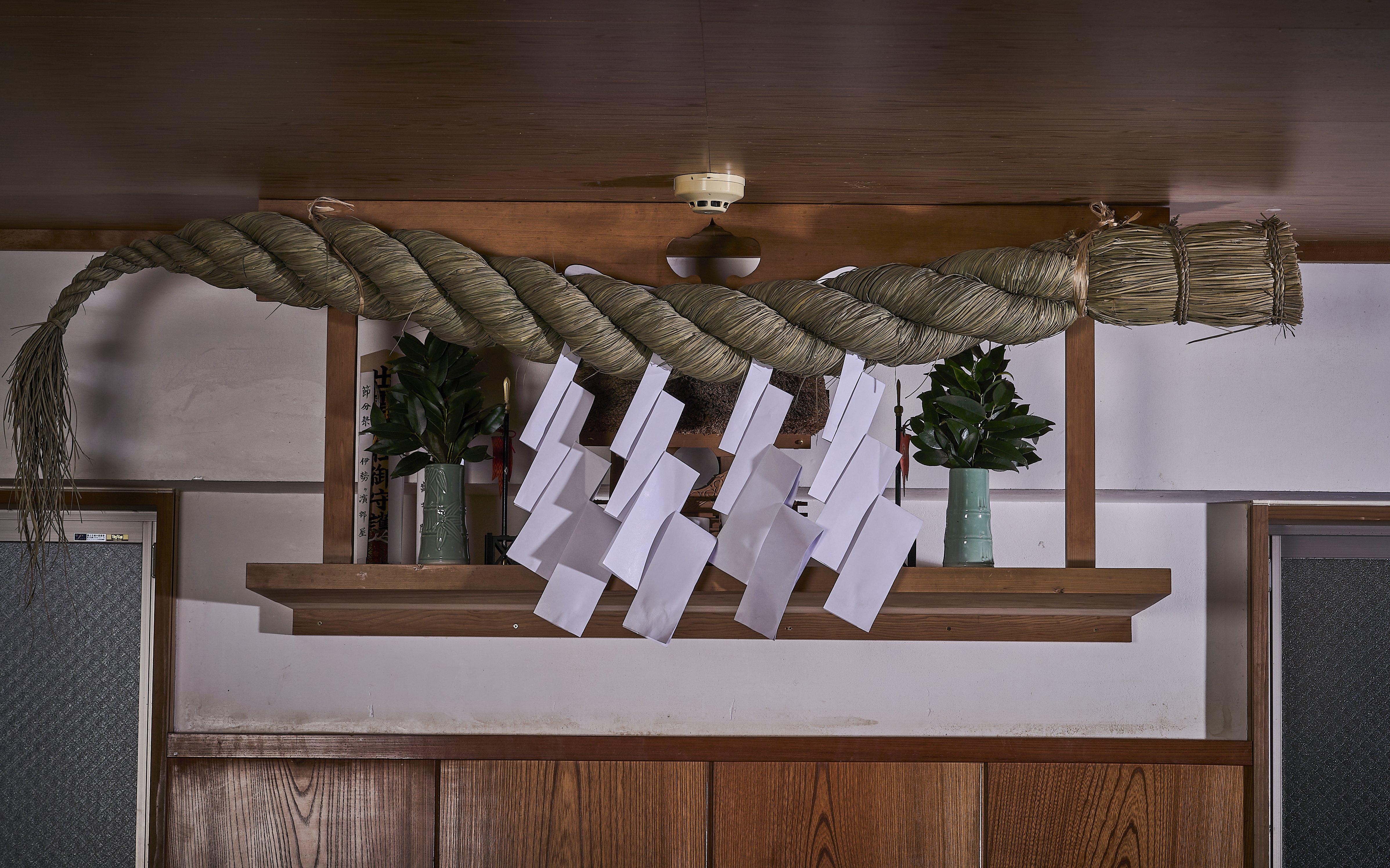 Decorative shimenawa rope with paper streamers in a Koto City sumo venue.