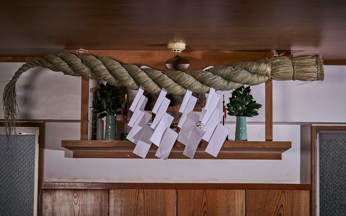 Decorative shimenawa rope with paper streamers in a Koto City sumo venue.