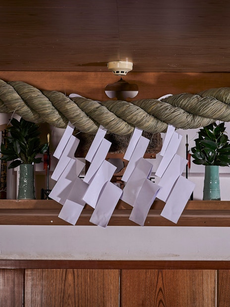 Decorative shimenawa rope with paper streamers in a Koto City sumo venue.