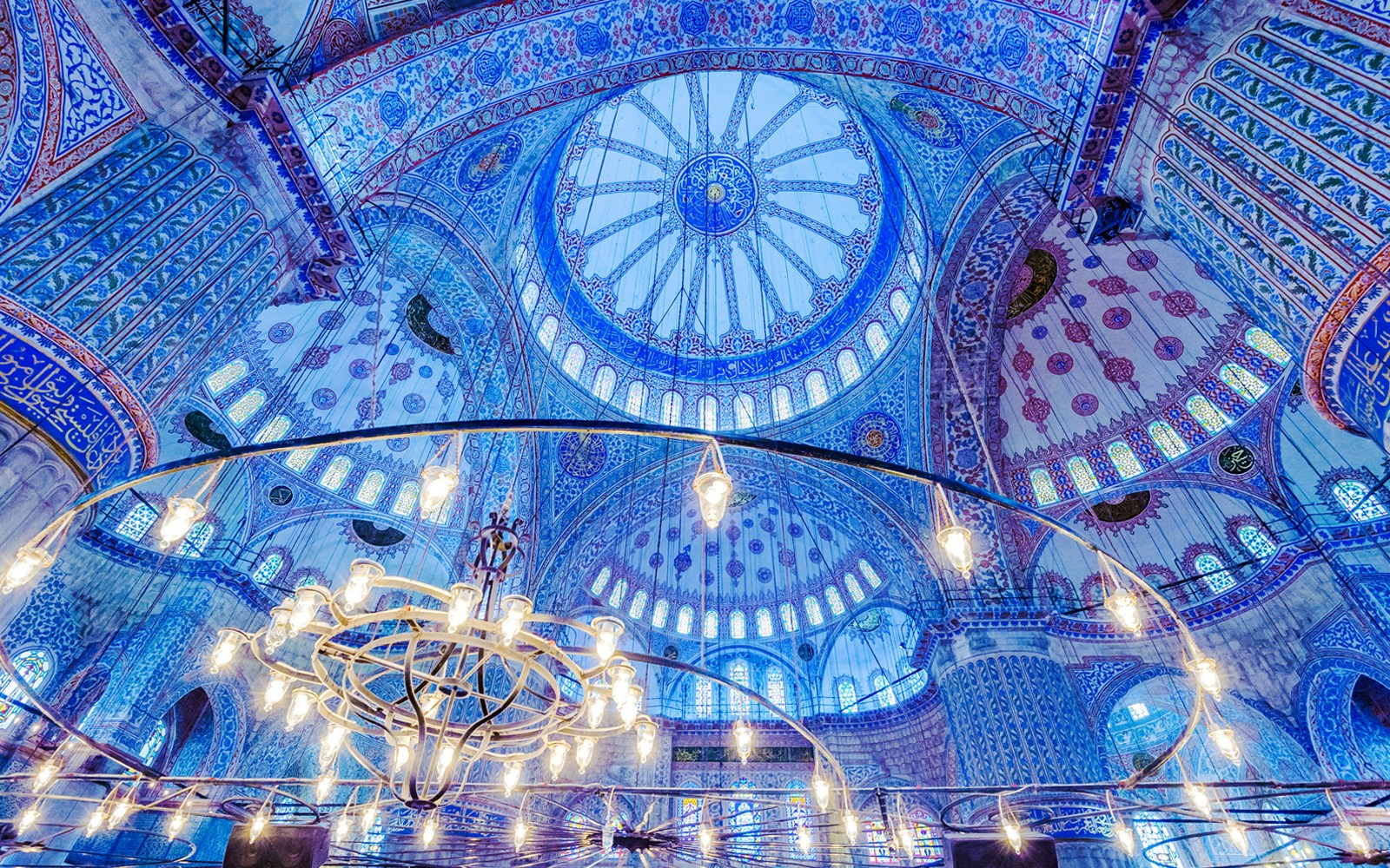 Blue Mosque interior with ornate blue tiles and central chandelier, Istanbul.