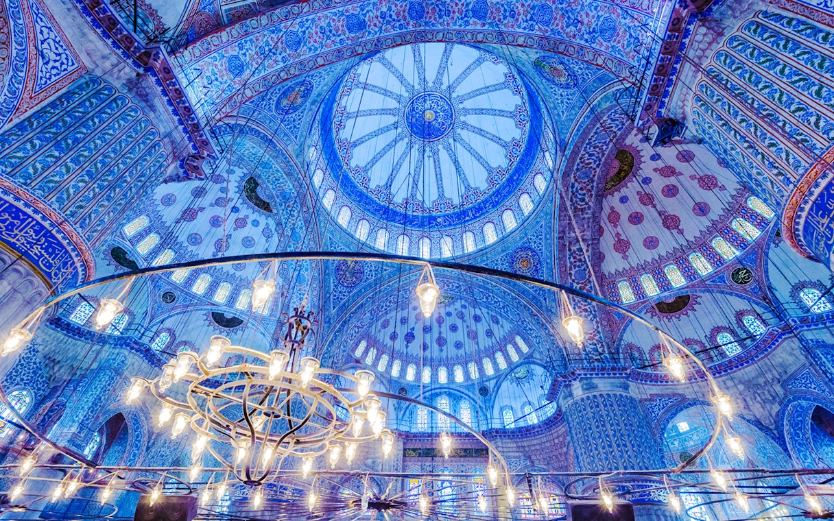 Blue Mosque interior with ornate blue tiles and central chandelier, Istanbul.