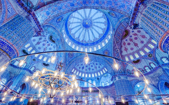 Blue Mosque interior with ornate blue tiles and central chandelier, Istanbul.