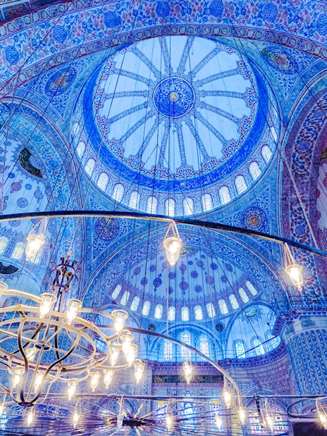 Blue Mosque interior with ornate blue tiles and central chandelier, Istanbul.