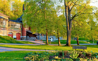 Historic building and lush park in Stockholm, part of the Royal Vikings city exploration game.