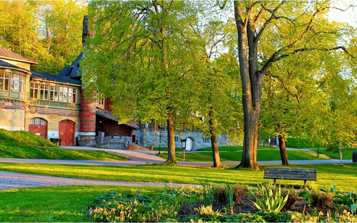 Historic building and lush park in Stockholm, part of the Royal Vikings city exploration game.