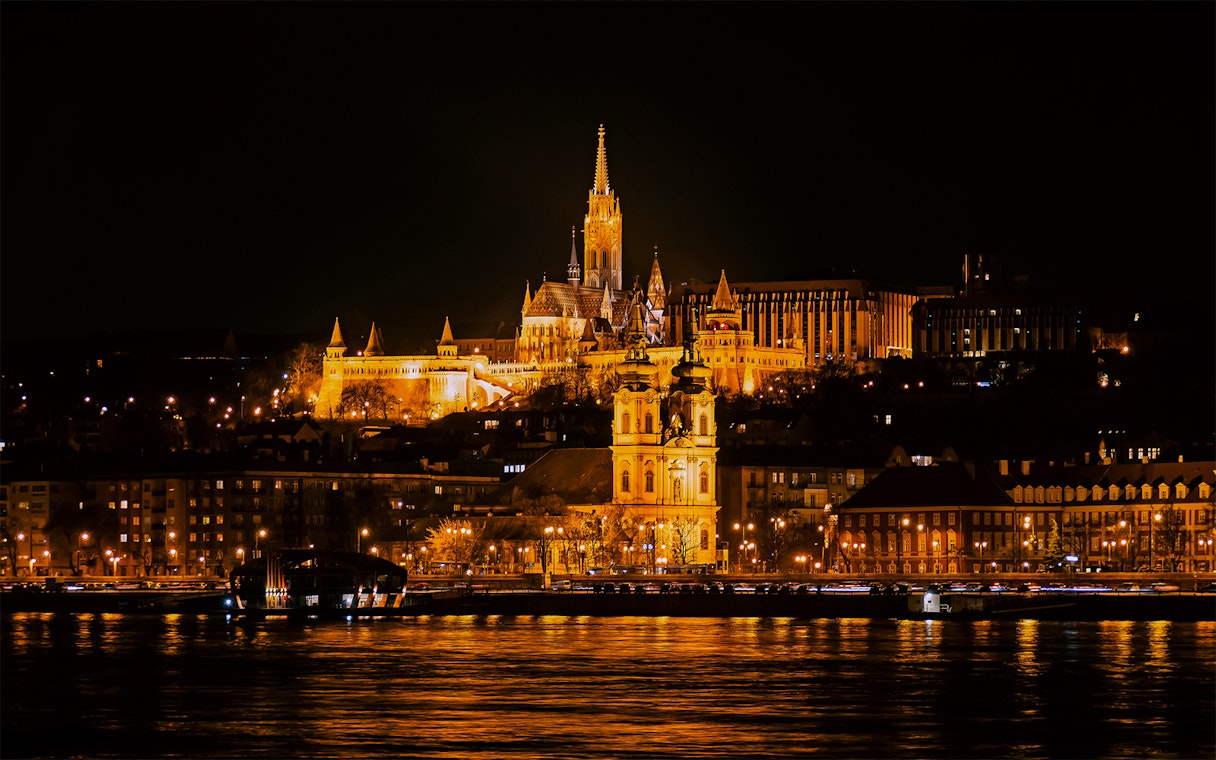 Matthias Church illuminated at night from a Danube River cruise in Budapest.