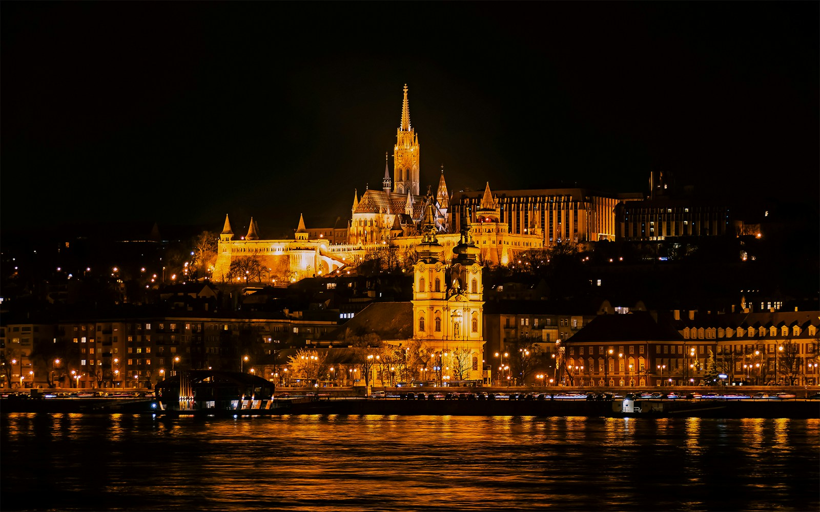 Matthias Church illuminated at night from a Danube River cruise in Budapest.