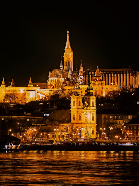 Matthias Church illuminated at night from a Danube River cruise in Budapest.