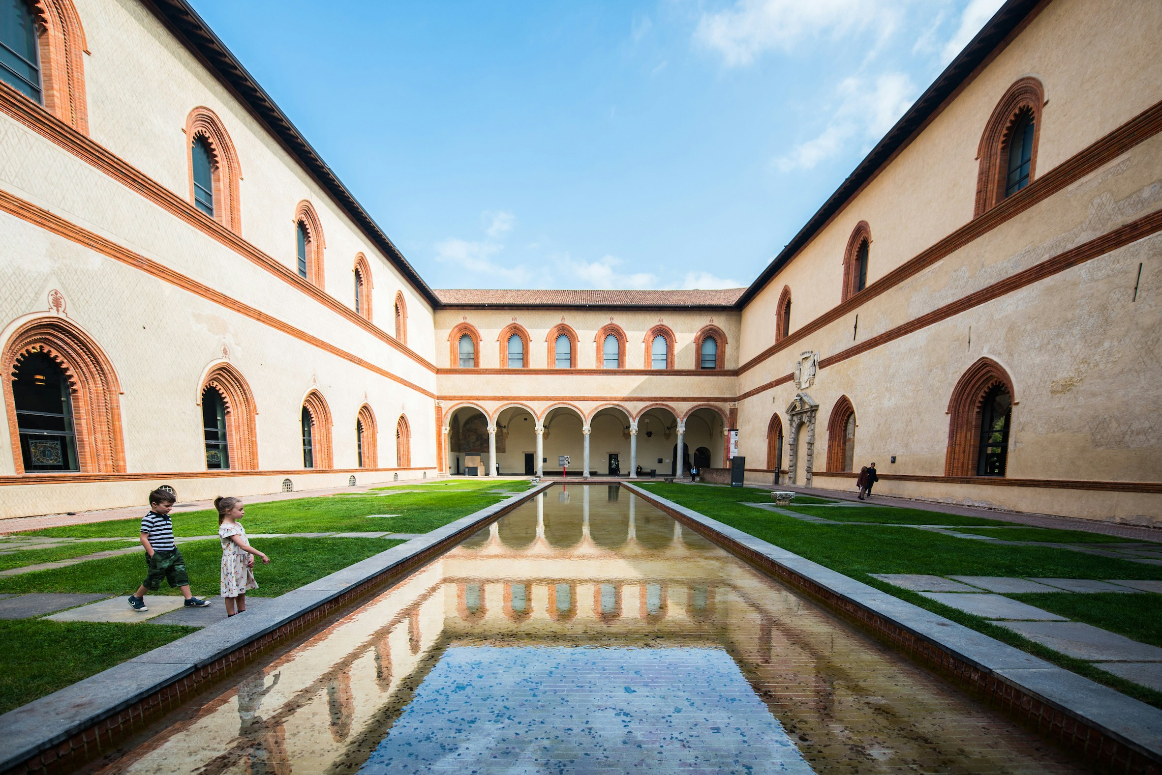 Courtyard of Pinacoteca del Castello Sforzesco with reflecting pool and children playing.